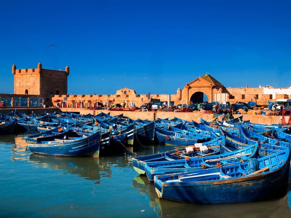 Blue fishing boats in Essaouira harbour below the medina ramparts